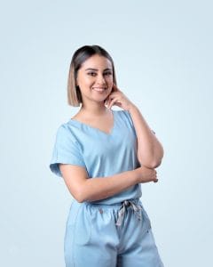 Mujer joven posando con una mano sobre su rostro frente a un fondo azul claro, viste una filipina azul cielo.